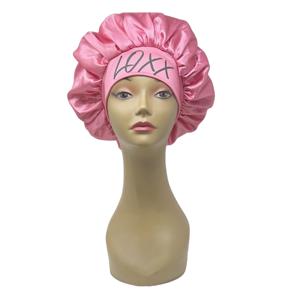 Pink satin bonnet with elastic band displayed on a mannequin head, ideal for protecting hair while sleeping.