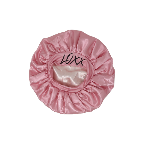 Pink satin bonnet with elastic band, perfect for protecting hair while sleeping.